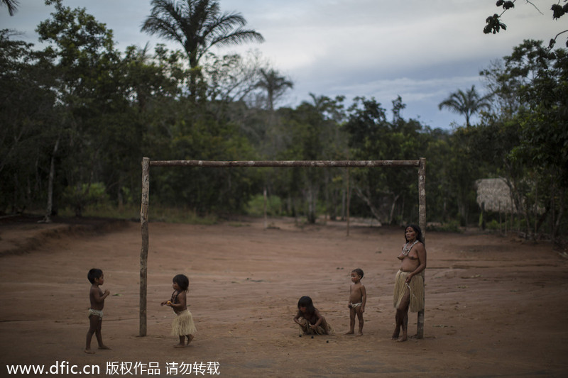 Des enfants et une femme venant de diverses tribus présents sur un terrain de football de la communauté autochtone de Tatuyo, près de Manaus, au Brésil, le 19 mai 2014. Manaus est l’une des villes h?tes de la Coupe du Monde 2014 au Brésil. [Photo/IC]