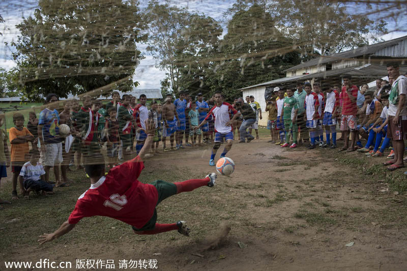 Ils sont plusieurs à assister à l’impuissance d’ un gardien de but devant un penalty, lors d’un tournoi de football dans la communauté de Sao Pedro, près de Manaus, au Brésil, le 18 mai 2014. Manaus est l’une des villes h?tes de la Coupe du Monde 2014 au Brésil. [Photo/IC]