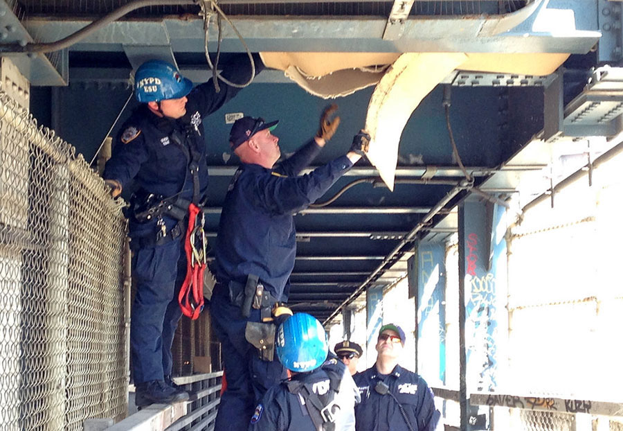 Des policiers new-yorkais démantèlent un campement construit par des sans-abri à l'intérieur du pont de Manhattan le 17 Avril 2014 à New York. Ce lieu été mis en lumière après qu’un vieil homme ait été aper?u pénétrer dans cet abri de fortune. 