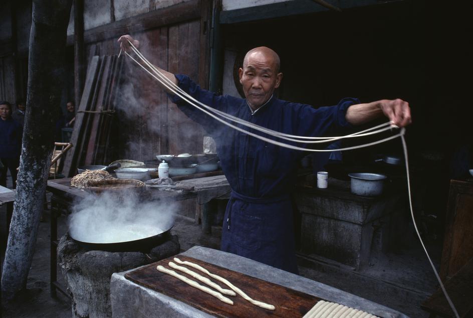 Une personne agée prépare des nouilles dans les rues de Chengdu (1980). 