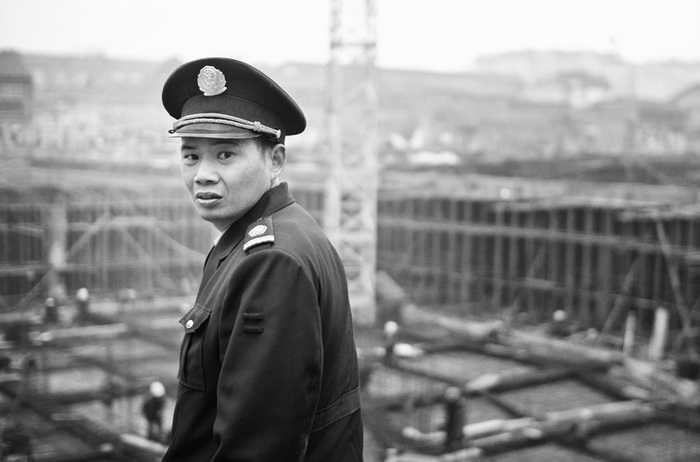 Les anciennes maisons du village vont dispara?tre. Le gardien du chantier plut?t méfiant sous l’objectif de la photographe.