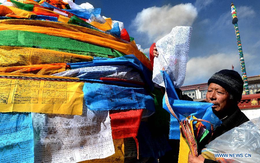Un dévot fixe des drapeaux de prière sur un mat près du temple de Jokhang à Lhassa, capitale de la région autonome chinoise du Tibet (sud-ouest du pays), le 11 février 2015.