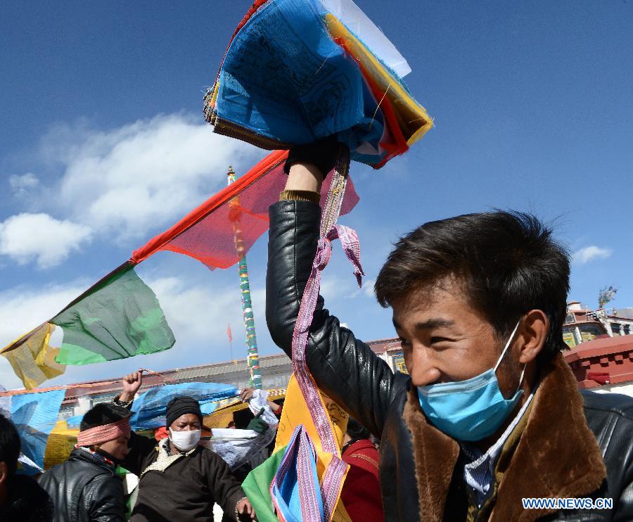 Des dévots tend des drapeaux de prière sur un poteau près du temple de Jokhang à Lhassa, capitale de la région autonome du Tibet dans le sud-ouest de la Chine, le 11 février 2015 .