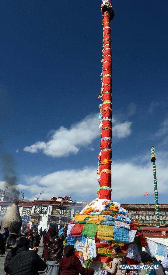 Des dévots tend des drapeaux de prière sur un poteau près du temple de Jokhang à Lhassa, capitale de la région autonome du Tibet dans le sud-ouest de la Chine, le 11 février 2015 .
