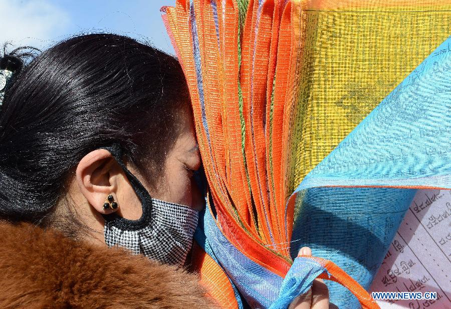 Une dévote place son front contre les drapeaux de prière, lors d’une prière près du temple de Jokhang à Lhassa, capitale de la région autonome chinoise du Tibet (sud-ouest du pays), le 11 février 2015.