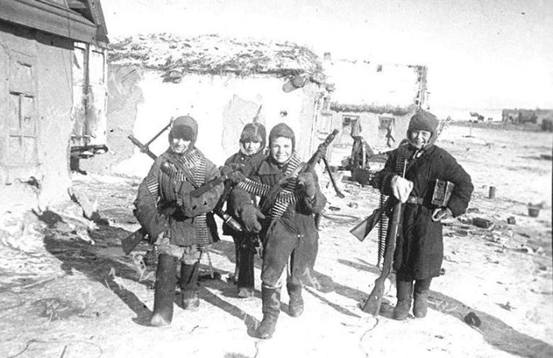 Un groupe d’adolescents de la campagne exhibent des mitrailleuses et des fusils allemands capturés ; photo prise à un endroit et à un moment inconnus.