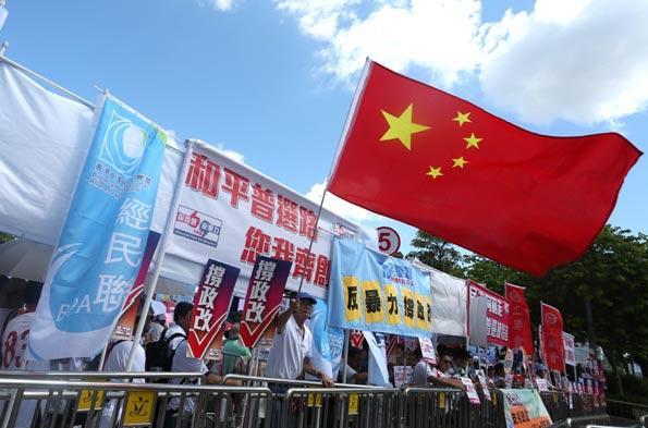 Des citoyens portent des pancartes et crient des slogans devant le siège du Conseil législatif, situé dans le quartier de l'Amirauté, pour soutenir le programme de réforme électorale du gouvernement de Hong Kong, le 17 juin 2015. Roy Liu / China Daily