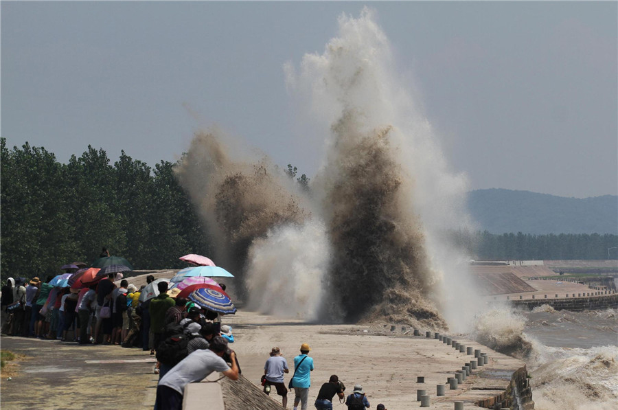 Les touristes se pressent sur une berge de la rivière Qiantang dans la province de Zhejiang (est de la Chine) pour assister à un impressionnant raz de marée de saison, le 2ao?t 2015. Avec des vagues atteignant jusqu'à 20 mètres de haut. [Photo/CFP]