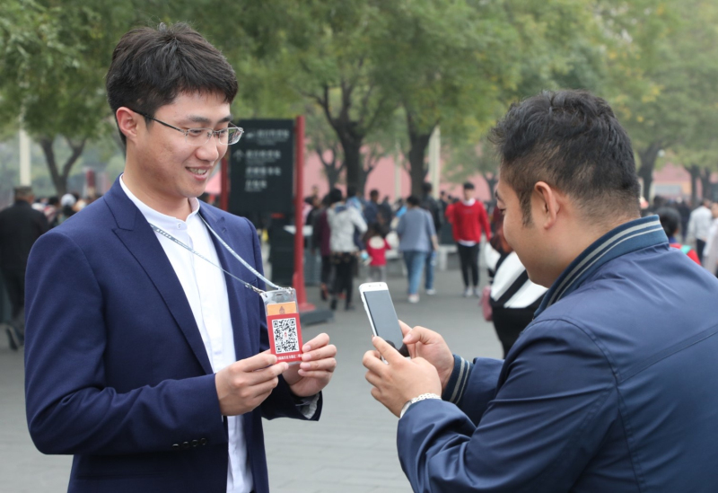 A Beijing, un touriste scanne le code en deux dimensions présenté par un membre du personnel du Musée national du Palais pour acheter son billet. Photo : Site internet du Musée du Palais.