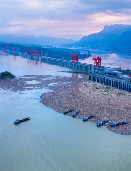 Des bateaux nettoient les objets flottants devant le barrage des Trois Gorges à Yichang, dans le Hubei
