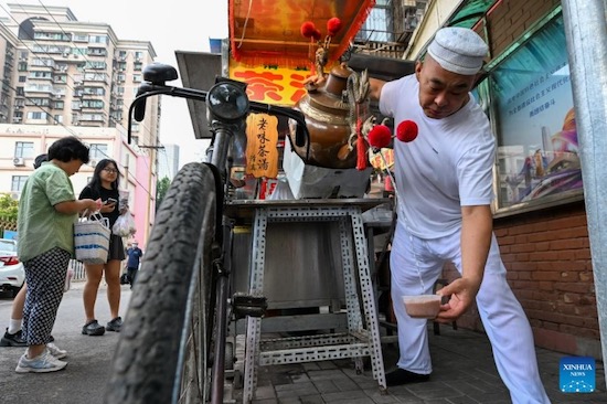 Un vendeur prépare une ??soupe de thé??. Bien que son nom l’indique, elle ne contient pas une seule goutte de thé. Pour réaliser ce plat, il faut verser de l’eau bouillante sur de la farine de millet, de la même manière que l’on préparerait du thé. C’est de là que provient le nom de chatang ou ??soupe de thé??. La chatang est généralement agrémentée de fruits secs, de graines de sésame, de sucre brun et de gelée de cenelle. (Xinhua/Sun Fanyue)