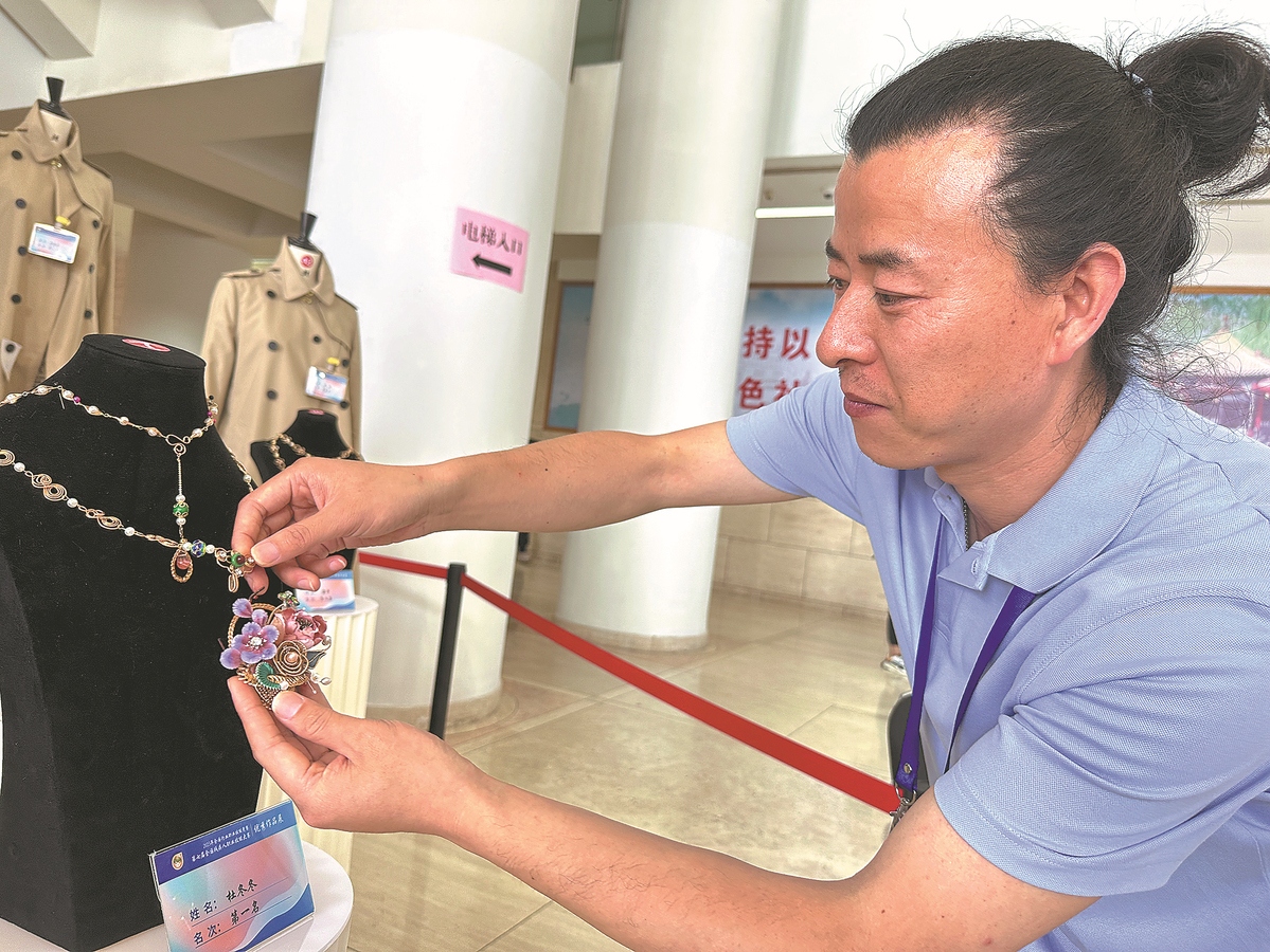Du Dongdong arrange un collier qu'il a con?u pour le concours. (Zhao Ruixue / China Daily)
