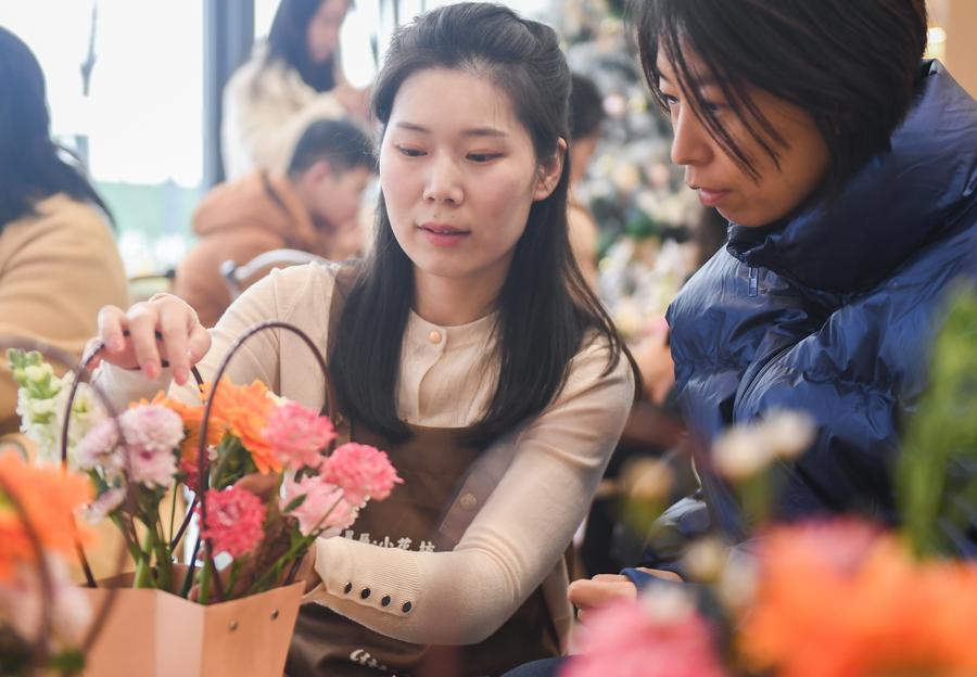 Huang Shasha (à gauche), un formateur, enseigne l'art floral lors d'un cours du soir dans la zone de développement de haute technologie du Lac Est de Wuhan, capitale de la province du Hubei (centre de la Chine), le 14 janvier 2024. (Du Zixuan / Xinhua)