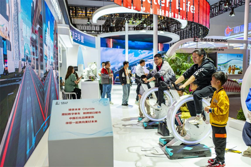 Des visiteurs essaient des vélos numériques sur le stand de Sinopec lors de l