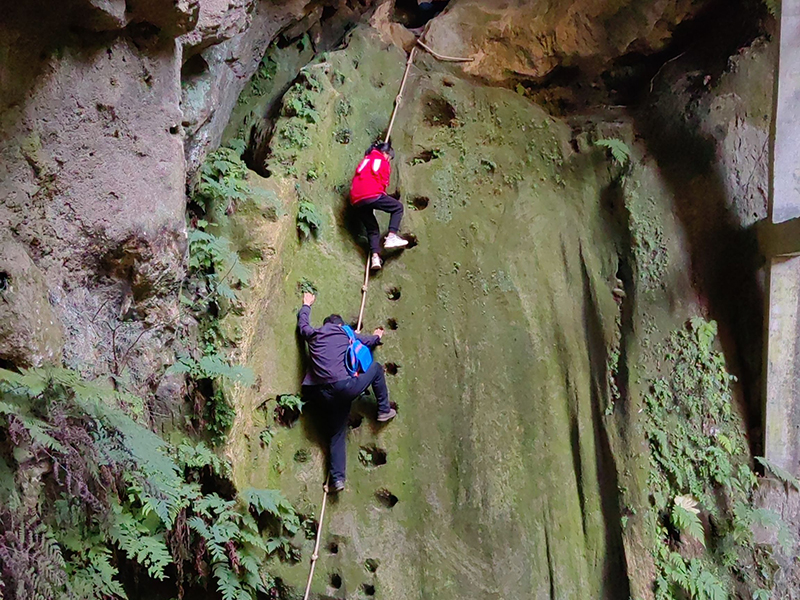 Un adulte accompagne une fillette pour gravir la falaise pour aller à l'école. (Photo d'archives)