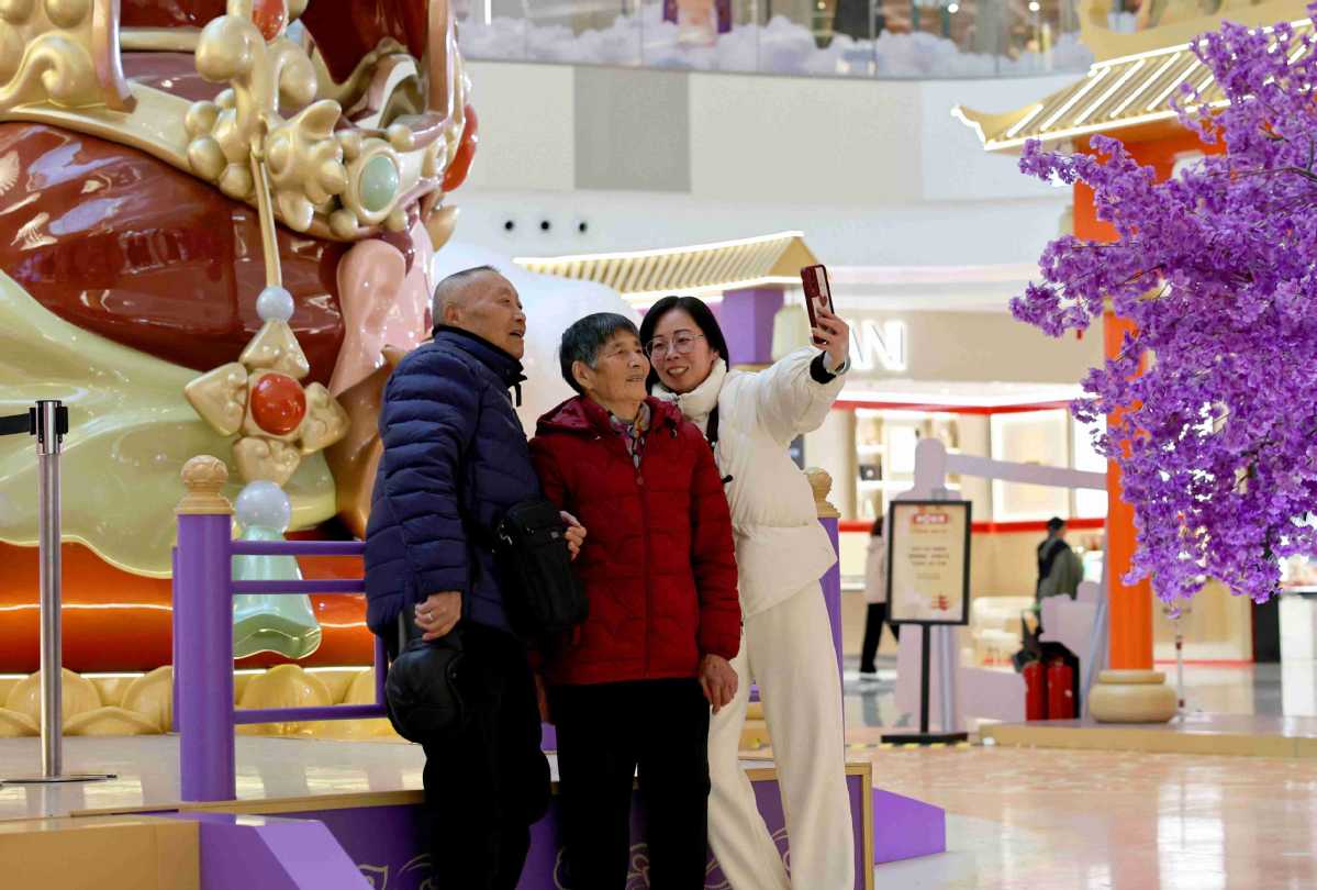 Des clients posent pour un selfie devant une décoration de la Fête du Printemps dans un centre commercial de Shanghai, le 28 janvier. (Photo / Xinhua)
