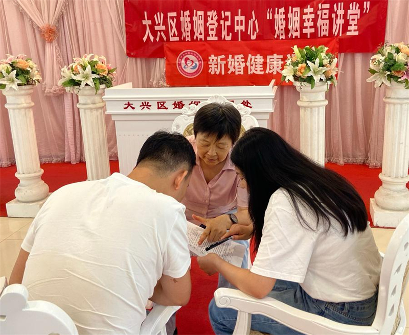 Photo prise avec un téléphone portable montrant Sui Yanling offrant des conseils pré-mariage dans le centre d'enregistrement des mariages du district de Daxing, le 7 ao?t 2024 à Beijing. (Photo / Xinhua)