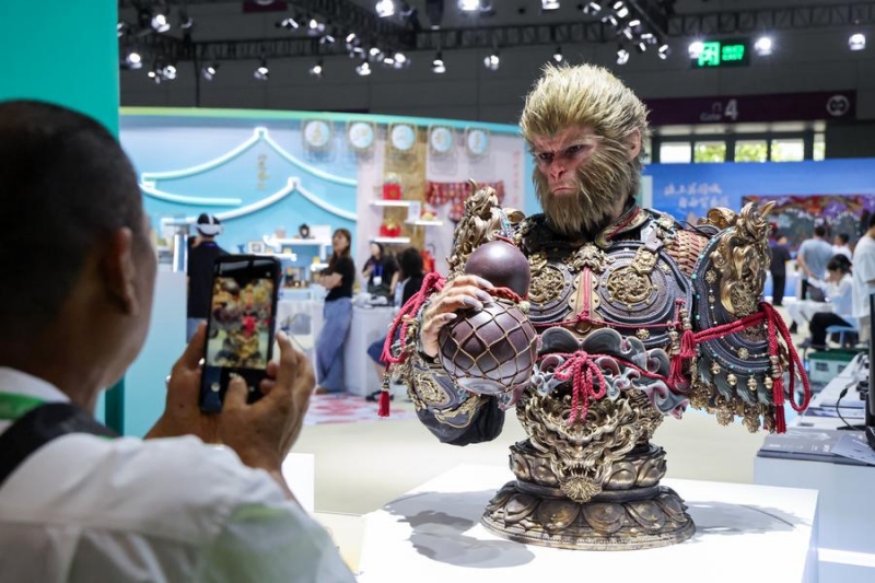 Un visiteur prend des photos d'un buste du personnage du jeu vidéo "Black Myth: Wukong" lors de la 21e Foire internationale des industries culturelles de Chine (Shenzhen), à Shenzhen, dans la province du Guangdong (sud de la Chine), le 23 mai 2025. (Photo : Liang Xu)