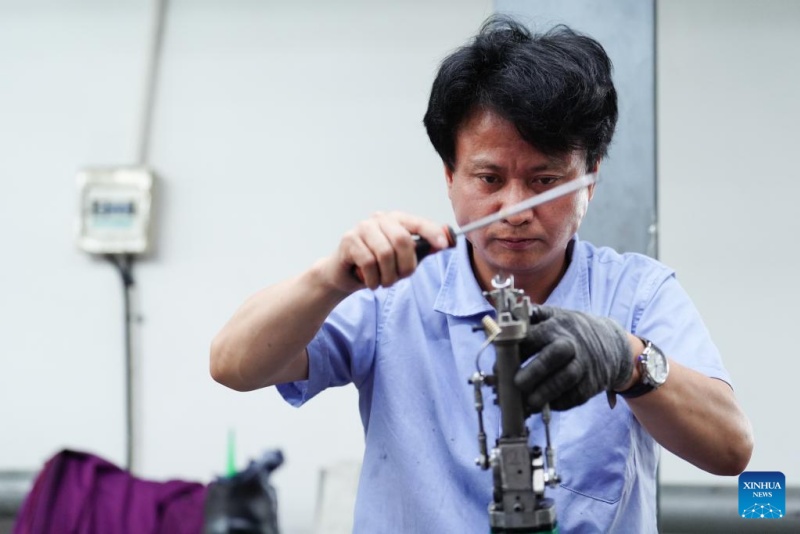 Un employé vérifie un outil utilisé pour la fabrication de tapis tibétains dans un atelier du groupe Shengyuan Carpet à Xining, capitale de la province du Qinghai (nord-ouest de la Chine), le 21 juillet 2025.(Qi Zhiyue/Xinhua)
