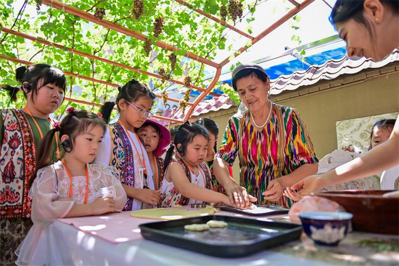 Des enfants découvrent la fabrication de spécialités locales lors d'un voyage scolaire dans la zone touristique folklorique de Kazanqi, à Yining, dans la préfecture autonome kazakhe d'Ili, dans la région autonome ou?goure du Xinjiang (nord-ouest de la Chine), le 23 juillet 2025. (Photo : Ding Lei)