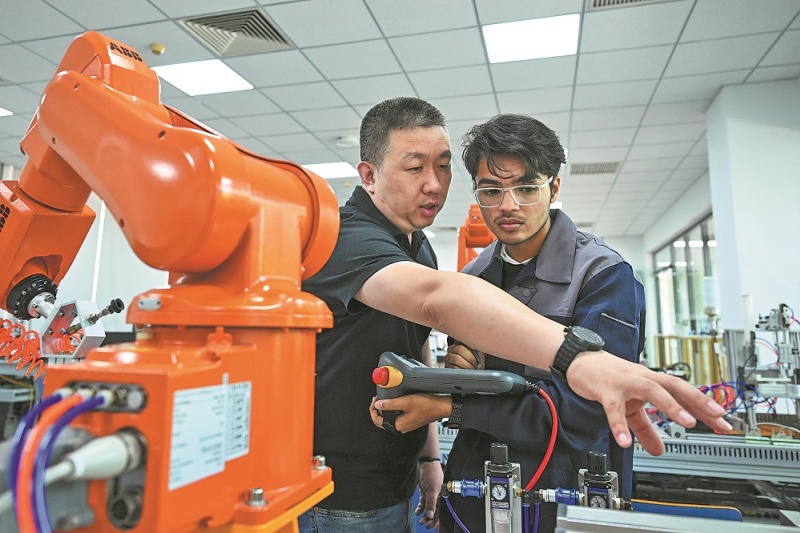 Un instructeur guide un étudiant pakistanais spécialisé dans l'automatisation électrique lors d'une session de formation à l'atelier Luban du Collège professionnel de technologie moderne de Tianjin (nord de la Chine).(Sun Fanyue/Xinhua)