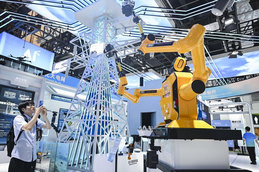 Un visiteur observe un robot destiné à la maintenance sous tension lors de la Conférence mondiale de l'IA 2025 à Shanghai, dans l'est de la Chine, le 28 juillet 2025. (Xinhua/Chen Haoming)