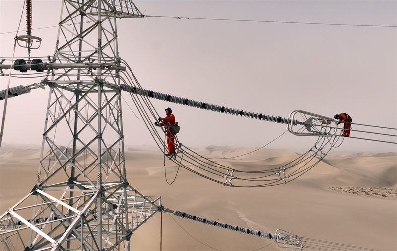 Xinjiang : des ouvriers électriciens corrigent les défauts du réseau avant sa mise en service dans le désert à Qiemo