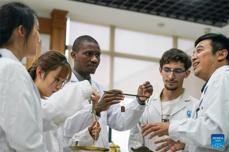 Pan Yinxing (1er à droite), ma?tre de conférences à l'Université de médecine chinoise de l'Anhui, enseigne à des étudiants étrangers comment utiliser une balance traditionnelle à Hefei, capitale de la province de l'Anhui (est de la Chine), le 16 octobre 2025. (Photo/Xinhua)