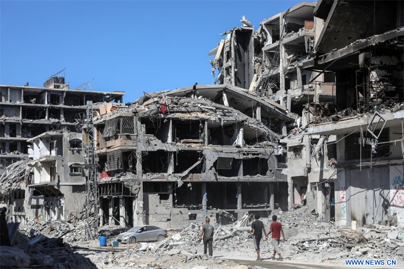 Des personnes sont vues dans une rue bordée de batiments détruits à Gaza, le 19 octobre 2025. Les Forces de défense israéliennes (FDI) ont indiqué dimanche dans un communiqué avoir lancé une nouvelle vague de frappes contre des cibles du Hamas dans le sud de la bande de Gaza. (Xinhua/Rizek Abdeljawad)